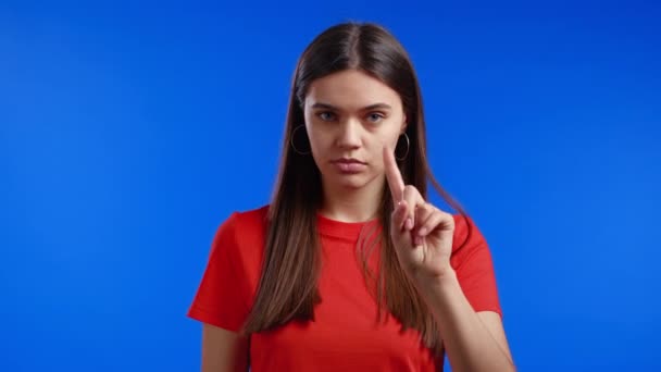 Retrato de mulher séria mostrando gesto de rejeição por sinal de dedo parada. Não brinques comigo. Menina grave isolado no fundo azul. — Vídeo de Stock