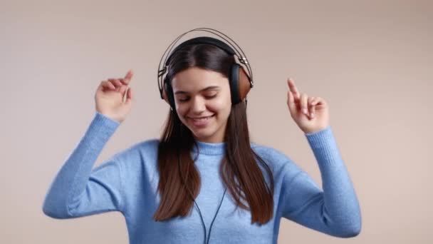 Charmante vrouw die danst met een koptelefoon op studioachtergrond. Schattig meisjesportret. Muziek, radio, geluk, vrijheid, jeugdconcept. — Stockvideo