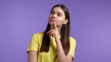Violet stüdyosunun arka planına bakan bir kadın. Düşünceli yüz ifadeleri. Çekici görünümlü güzel bir model.
