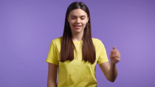 Жінка показує великий палець на фіолетовому тлі. Позитивна молода дівчина посміхається фотоапарату. Переможець. Успіх. Мова тіла . — стокове відео