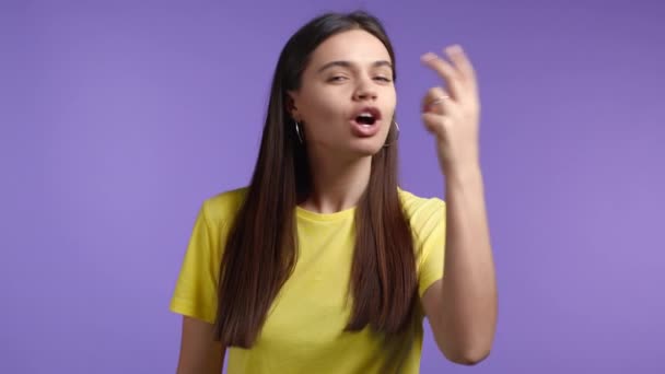 Mulher de t-shirt amarela fazendo um gesto delicioso e perfeito. A menina admira o gosto da comida italiana no fundo de estúdio violeta. Conceito de Bellissimo. — Vídeo de Stock