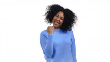 Afrikalı kadın çok mutlu ve mutlu. Zaferin evet jestini gösteriyor. Sonuç elde etti, hedeflere ulaştı. Beyaz stüdyo geçmişindeki heyecanlı ve mutlu bayana şaşırdım. Büyük ikramiye konsepti.