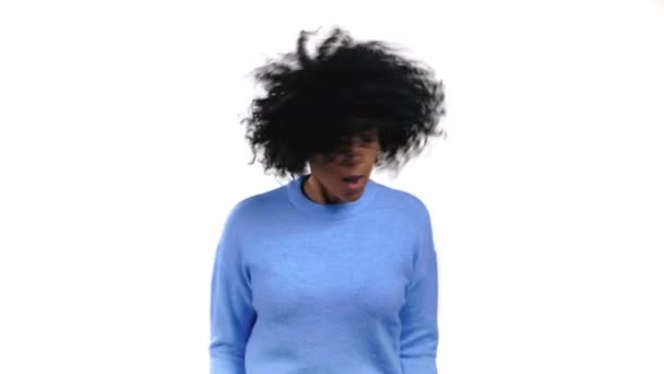 Mulher de raça mista com penteado afro dançando positivo no fundo do estúdio branco. Bonita modelo feminina de camisola azul. Festa, felicidade, liberdade, conceito de juventude. — Vídeo de Stock