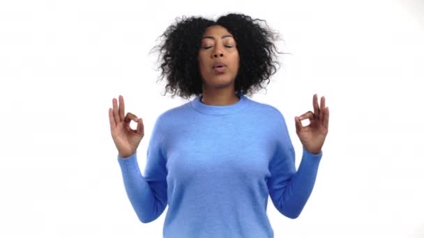 Mulher africana calma em azul relaxante, meditando. Ela se acalma, respira profundamente com mudra om no fundo do estúdio. Conceito de ioga. — Vídeo de Stock