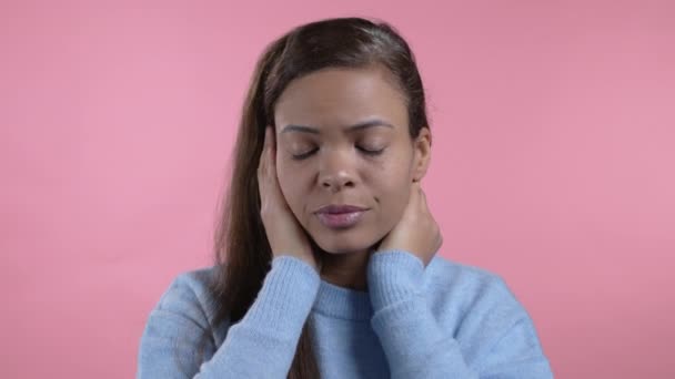Baş ağrısı çeken Afrikalı bir kadının portresi, pembe stüdyo portresi. Ellerini başının üstüne koyan bir kız. Migren sorunları, ilaç, hastalık kavramı — Stok video