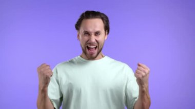 Kazanan adam çok mutlu ve mutlu. Zaferin evet jestini gösteriyor. Sonuç elde eden adam, hedefler. Mor arka planda heyecanlı, mutlu çocuk.