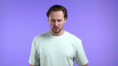 Menekşe arka planda öfkeli bir adam. Stres ve öfke içindeki Avrupalı bir adam, saldırgandır ve kameraya tiksinerek bakar.