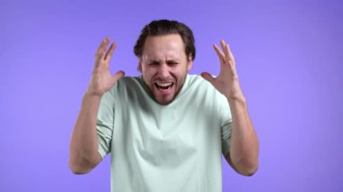 Genç Avrupalı bağıran adam menekşe arka planda izole halde. Stresli ve depresif adam kameraya doğru yüksek sesle bağırıyor. 4k