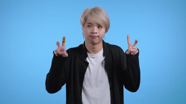 Aziatische man tonen met handen en twee vingers lucht citeert gebaar, buig vingers geïsoleerd over blauwe achtergrond. Geen grappig, ironisch en sarcastisch concept. — Stockvideo