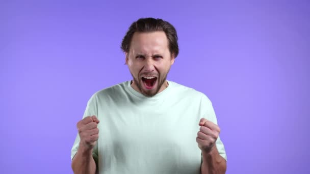 Mann in Rage auf violettem Hintergrund. Europäischer Typ im Stress, er ist aggressiv und blickt mit Hass in die Kamera — Stockvideo