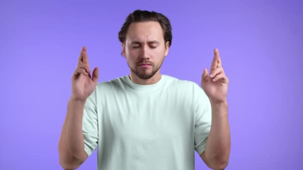 Bel homme priant avec les doigts croisés sur fond violet. Le gars suppliant quelqu'un de satisfaire ses désirs, aider à. — Video
