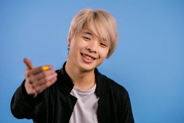 Hey sen, buraya gel Asyalı stil adamı. Koreli adam ona katılır mısın diye sorar, el sıkışma hareketi ile çağırır. O, gelmeye davet ederek şakacı flörtöz görünüyor. Mavi stüdyo arka planı.