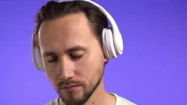 Yakışıklı genç adam müzikten hoşlanıyor. Stüdyoda kulaklıklarla gülüyor. Violet 'in arka planında. Dans, radyo konsepti.