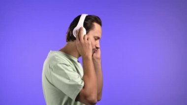 Yakışıklı genç adam müzikten hoşlanıyor. Stüdyoda kulaklıklarla gülüyor. Violet 'in arka planında. Erkek dansı, radyo konsepti..