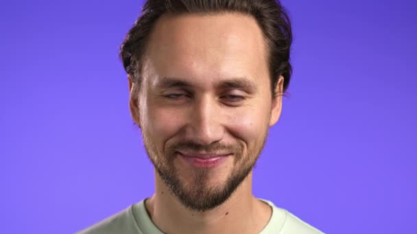 Portret van vrolijke Europese man op zoek naar camera.Jonge knappe aardige kerel glimlachen in de studio op violette achtergrond. — Stockvideo