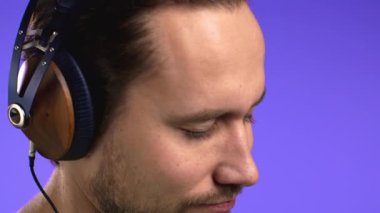 Yakışıklı genç adam müzikten hoşlanıyor. Stüdyoda kulaklıklarla gülüyor. Violet 'in arka planında. Yakın plan yüz. Dans, radyo konsepti.