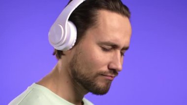 Yakışıklı genç adam müzikten hoşlanıyor. Stüdyoda kulaklıklarla gülüyor. Violet 'in arka planında. Dans, radyo konsepti.