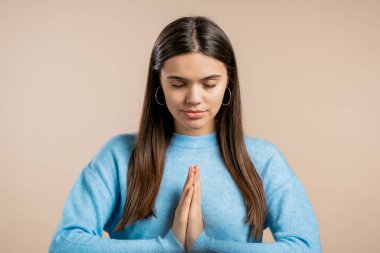 Elleriyle dua eden sakin bir kadın duayı ve minnettarlığı simgeliyor. Mudra. Yoga konsepti. Bej rengi ışık stüdyo arkaplanı.