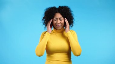 Baş ağrısı çeken Afrikalı bir kadının portresi, mavi stüdyo resmi. Ellerini başının üstüne koyan bir kız. Migren sorunları, ilaç, hastalık kavramı