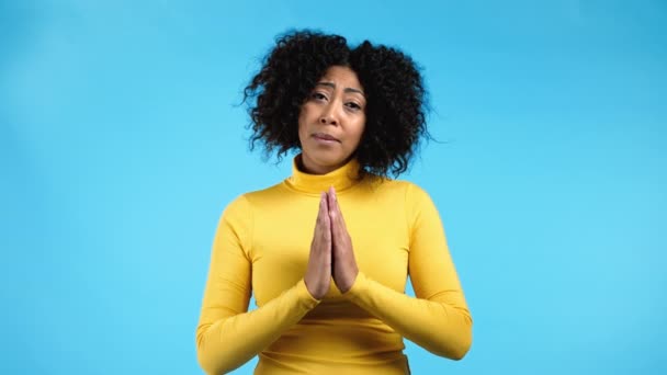 Mujer de raza mixta rezando sobre fondo azul. Afro Chica rogando a Dios para hacer sus sueños realidad, ayudar con. — Vídeo de stock