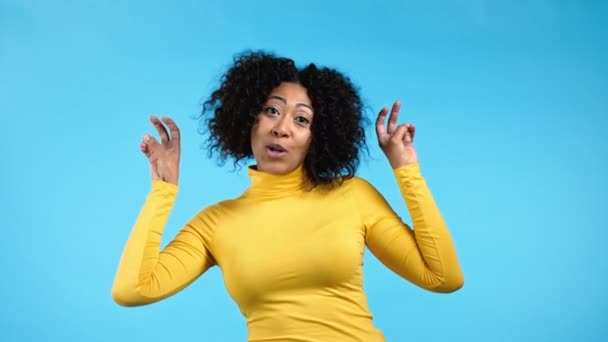 Mujer de raza mixta mostrando con las manos y dos dedos comillas de aire gesto, doblar los dedos aislados sobre fondo azul. No es divertido, ironía y sarcasmo concepto. — Vídeos de Stock