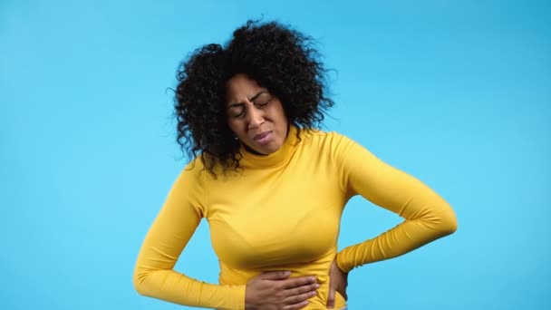 Young african woman squeezing belly with hands because of abdominal pain. Lady suffering from stomach ache. Healthcare, problem with menstrual period cramps or bowel flatulence concept — Stock Video