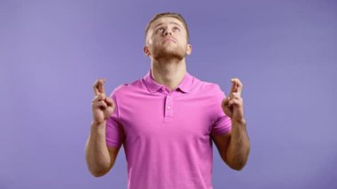 Genç adam menekşe arkaplanı için dua ediyor. Pembe gömlekli adam, birine arzularını tatmin etmesi için yalvarıyor..