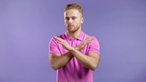 Retrato de un hombre serio desaprobando sin cruce de manos signo hacer basta, negación, suficiente gesto. Negando, rechazando, en desacuerdo. Retrato de chico guapo sobre fondo violeta — Vídeos de Stock