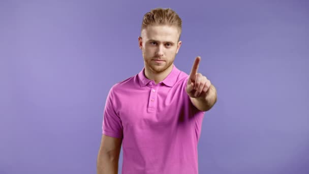 Portret poważnego mężczyzny, który odrzuca gest po znaku stopu. Facet w różowym ubraniu odizolowany na różowym tle. — Wideo stockowe