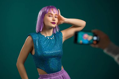 Gülümseyen vlogger hipster kadın kendini mavi arka planda akıllı telefon kamerasının önünde dans ederken videoya kaydediyor. Nüfuz Edici komik sosyal medya klibi yapıyor