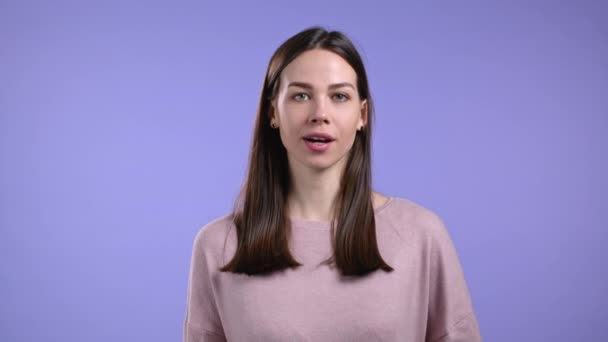 Mooie vrouw met duim omhoog als teken over violette studio achtergrond. Positief jong meisje met natuurlijk haar glimlacht naar de camera. Winnaar. Succes. Lichaamstaal. — Stockvideo