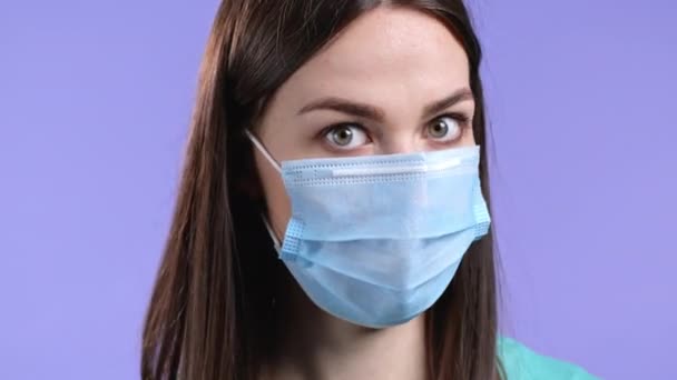 Onflexibele vrouw met beschermende gezichtsmasker afkeuren zonder hoofdteken, knikt hoofd afkeurend. Ontkennen, Afwijzen, Oneens, Portret van mooi meisje op violette studio achtergrond. — Stockvideo