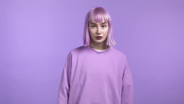 Porträtt av millenial trendig kvinna med färgat violett hår på lila studio bakgrund. En seriös ung flicka som tittar in i kameran. Fantastisk make-up och total pastell outfit — Stockvideo