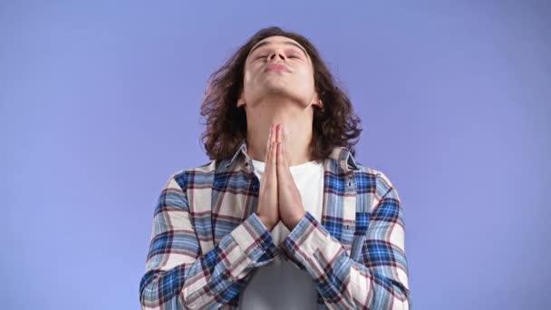 청년 이 보라색 배경으로 기도하고 있습니다. 머리를 길게기르고 구걸하는 사람은 자신의 욕구를 충족시켜 주고 도움을 준다. — 비디오