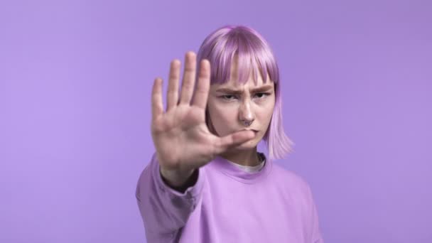Egy csinos nő nem helyesli a kézjegyét. Tagadása, elutasítása, egyet nem értés, portré gyönyörű lány festett lila haj ibolya háttér — Stock videók