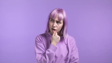 Mor boyalı saçlı kadının Violet stüdyosunun arka planına baktığını düşünüyorum. Düşünceli yüz ifadeleri. Çekici görünümlü güzel bir model. 