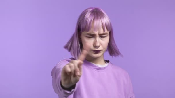 Egy komoly, trendi nő portréja, amint elutasító gesztust mutat a mutatóujjával. Lány elszigetelt ibolya háttér. — Stock videók