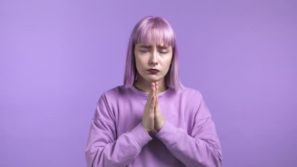 Jolie femme à la mode priant sur fond violet. Fille aux cheveux violets teints suppliant Dieu de réaliser ses rêves, aidez-moi avec. — Video