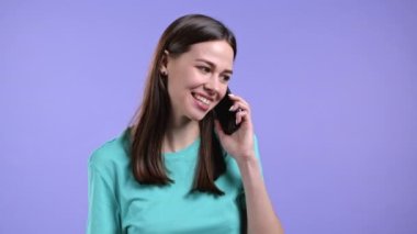 Genç bayan telefonda gülümseyerek konuşur. Kız kucağında ve akıllı telefon kullanıyor. Violet stüdyo geçmişi.