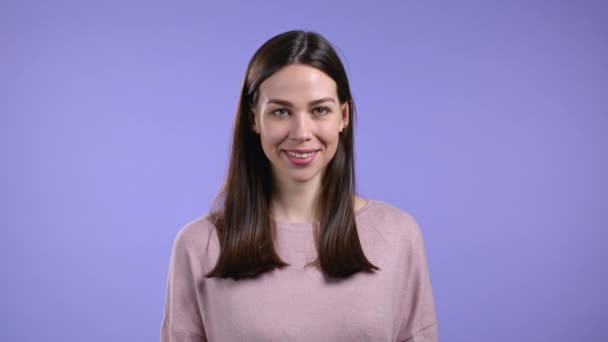 Porträtt av kvinna över violett studio bakgrund. Positiv ung flicka med naturligt hår ler mot kameran. — Stockvideo
