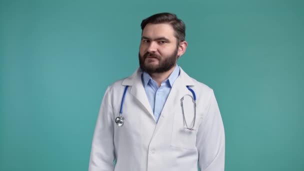 頭のサイン、否定的なジェスチャーを示さないプロの医療白衣の医師の肖像画。否定する、同意しない。ドク・マン・ノーズは青い背景に隔離されてる. — ストック動画