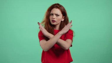Çapraz el işareti olmadan onaylamayan güzel bir kız Basta, Negatif, bu kadar jest yeter. Reddetmek, reddetmek, anlaşmazlık, yeşil arka planda güzel bir kızın portresi