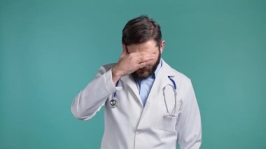 Doktor adam facepalm hareketi yapıyor, hayır, unuttum. Mutsuz doktor üzüntü, pişmanlık, drama, başarısızlık hissediyor. Mavi duvarda izole edilmiş.