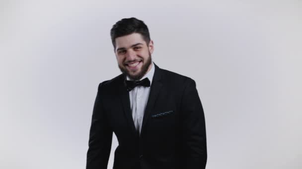 Ritratto di affascinante uomo georgiano in smoking nero che guarda alla macchina fotografica. Giovane bel ragazzo carismatico con la barba sorridente in studio su sfondo bianco. — Video Stock