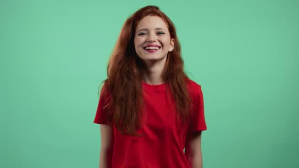 Retrato de mujer se ríe sobre fondo de estudio verde. Chica joven positiva con el pelo rojo sonríe a la cámara. — Vídeos de Stock