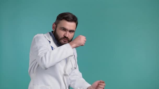 Gelukkige dokter grappig dansen, succes en geluk op het werk. Knappe doc man met baard in professionele medische witte jas is geïsoleerd op blauwe studio achtergrond. — Stockvideo