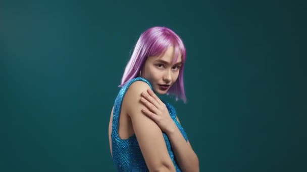 若いセクシーな女性が染め紫色の髪型は、カメラを探して、いちゃつく。美しいモデル女性オンブルースタジオの背景. — ストック動画