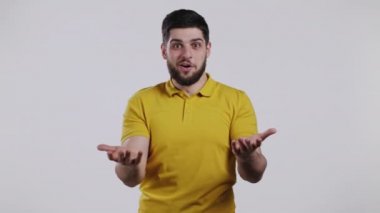 İnsan şaşkınlığı tasvir eder, zevkli yüz efektini gösterir. Sarı giysili mutlu adam şaşırdı. Beyaz arka planda yakışıklı erkek şok modeli.