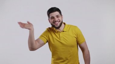 Genç adam el sallıyor. Merhaba. Selamlar, kameraya merhaba deyin. Beyaz stüdyo geçmişinde sakalı olan adam..