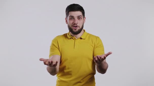 El hombre representa asombro, muestra WOW deleite efecto de la cara. Sorprendido chico feliz emocionado en ropa amarilla. Hermoso modelo chocado masculino sobre fondo blanco. — Vídeos de Stock